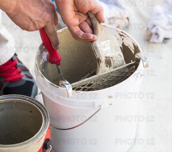 Professional painter loading paint onto his brush from A bucket