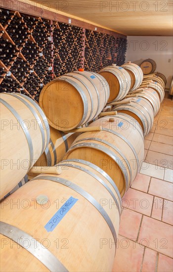 Wine barrels and bottles age inside dark cellar