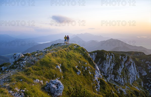Two hikers at the summit of the Benediktenwand at sunset