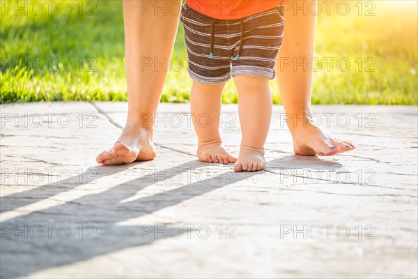 Mother and baby feet taking steps outdoors