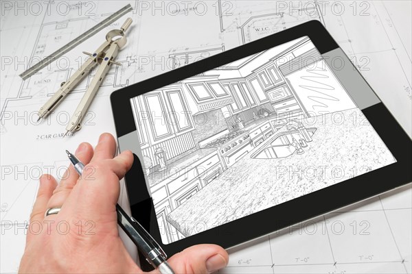 Hand of architect on computer tablet showing custom kitchen illustration over house plans
