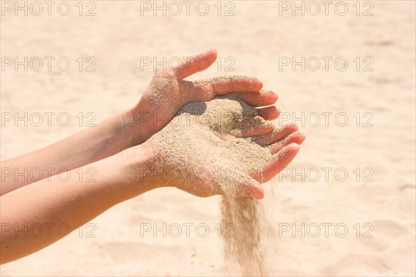 Sand running through hands on beach