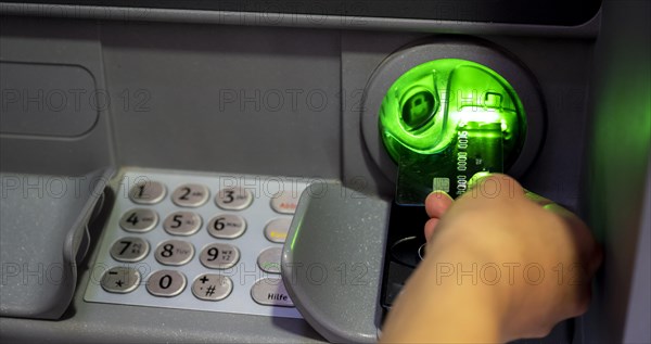 Hand pushes credit card into an ATM