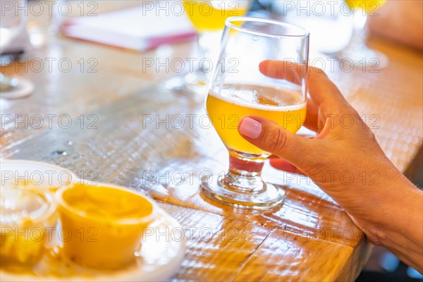 Female hand holding glass of micro brew beer at bar