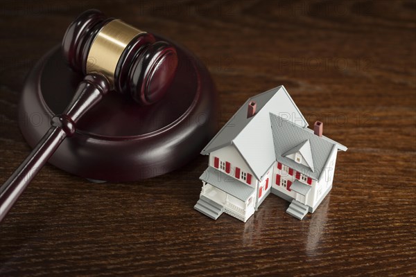 Gavel and small model house on wooden table