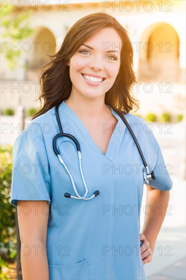 Portrait of young adult female doctor or nurse wearing scrubs and stethoscope outside