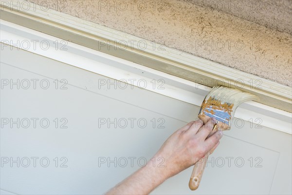 Professional painter cutting in with A brush to paint garage door frame