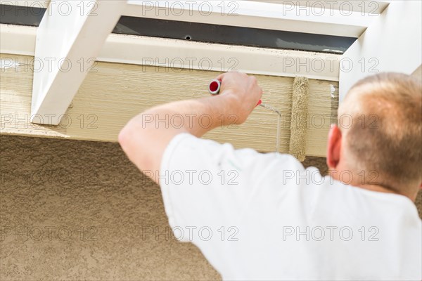 Professional painter using A small roller to paint house fascia