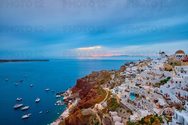 Famous greek iconic selfie spot tourist destination Oia village with traditional white houses and windmills in Santorini island on sunset in twilight