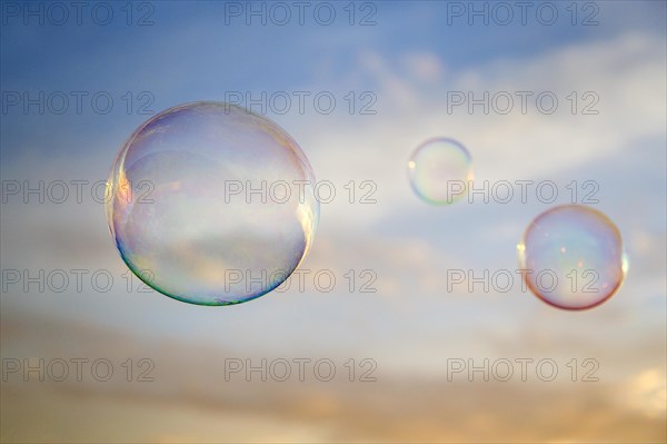 Three soap bubbles floating outdoors at sunset