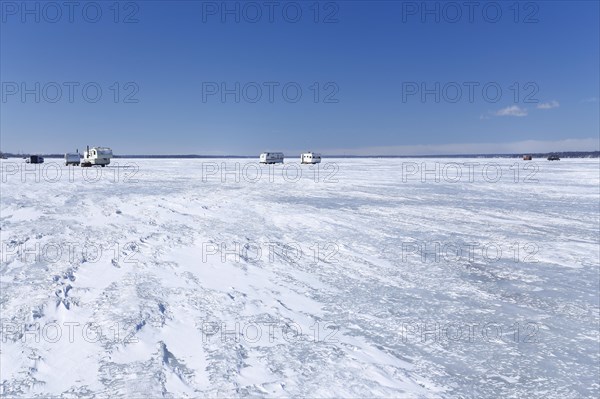 Fishing huts on a wide and frozen riverscape