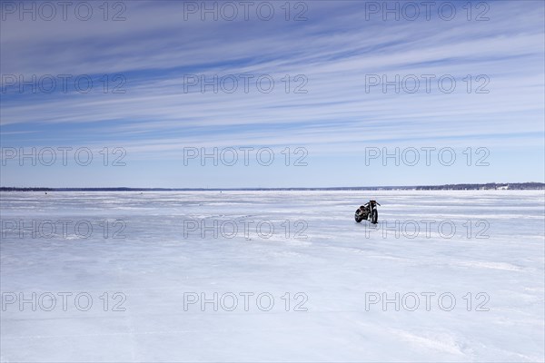 Lone motorcycle on a wide and frozen riverscape