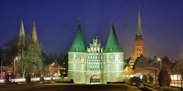 Green illuminated Holsten Gate with St. Mary's Church