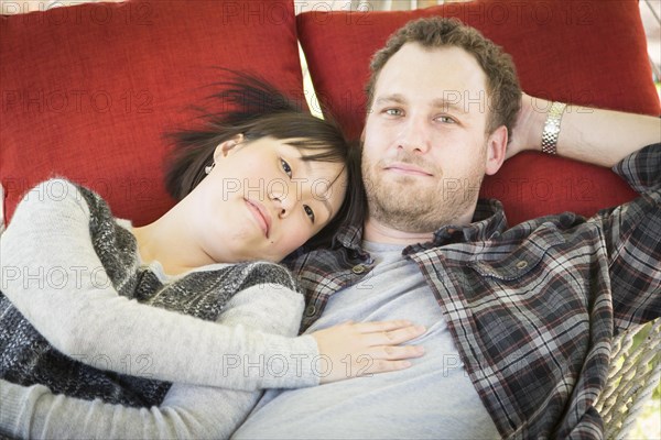 Happy mixed-race couple relaxing in a hammock outside