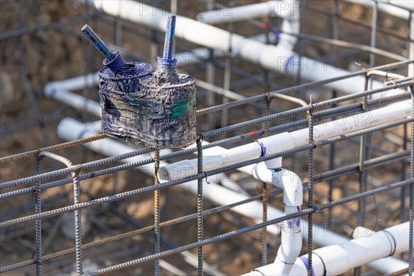 Newly installed PVC plumbing pipes and steel rebar configuration at construction site