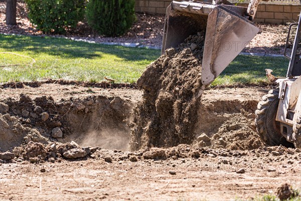 Small bulldozer digging in yard for pool installation