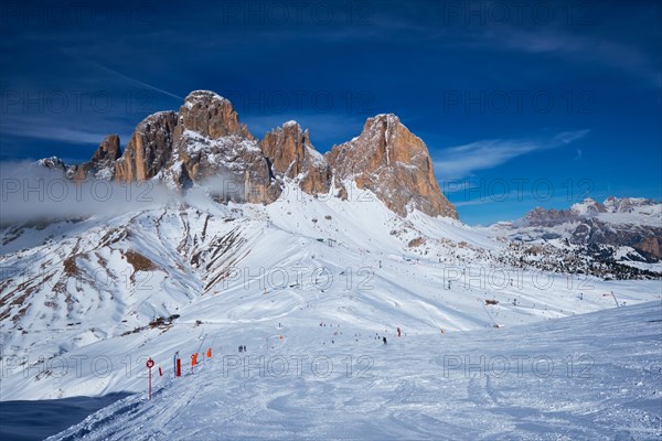 View of a ski resort piste with people skiing in Dolomites in Italy