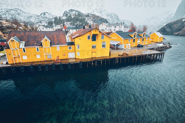 Panorama of Nusfjord authentic fishing village with yellow rorbu houses in Norwegian fjord in winter. Lofoten islands