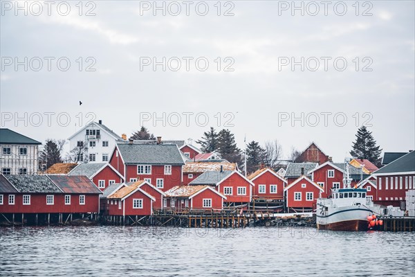 Reine fishing village on Lofoten islands with red rorbu houses in winter with snow with fishing boats. Norway
