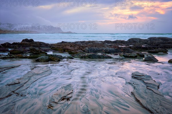 Beach of Norwegian sea on rocky coast in fjord on sunset. Skagsanden beach