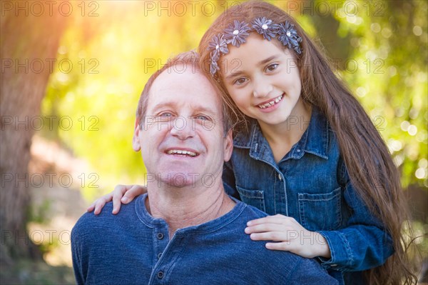 Cute young mixed-race girl and caucasian grandfather having fun outdoors