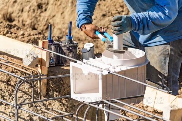 Plumber using wrench to install PVC pipe at construction site