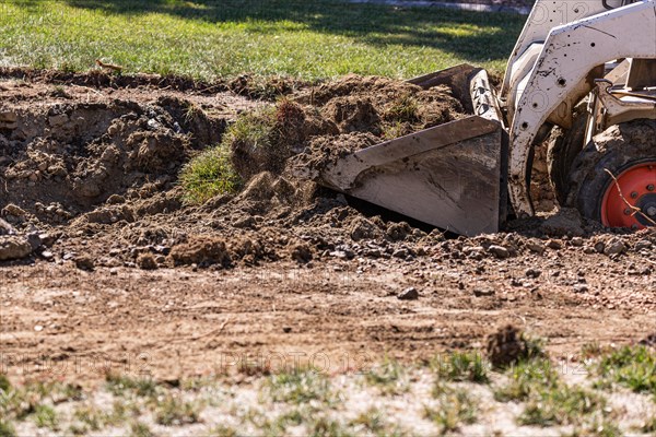 Small bulldozer digging in yard for pool installation