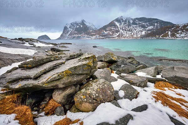 Rocky coast of fjord of Norwegian sea in winter with snow. Haukland beach