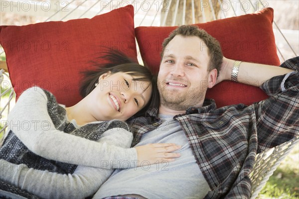 Happy mixed-race couple relaxing in a hammock outside