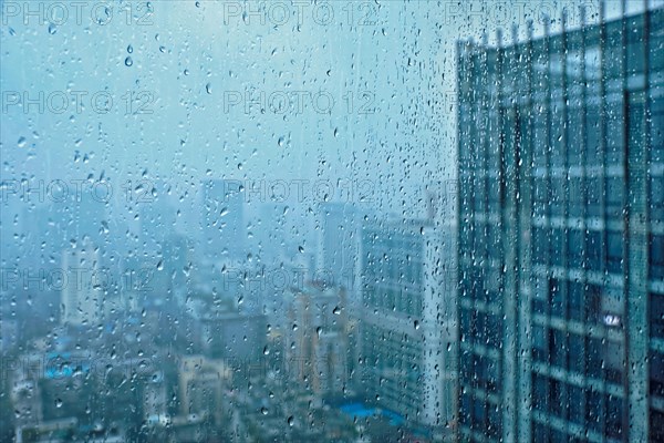 Rain water drops droplets on window glass texture with skyscrapers in background