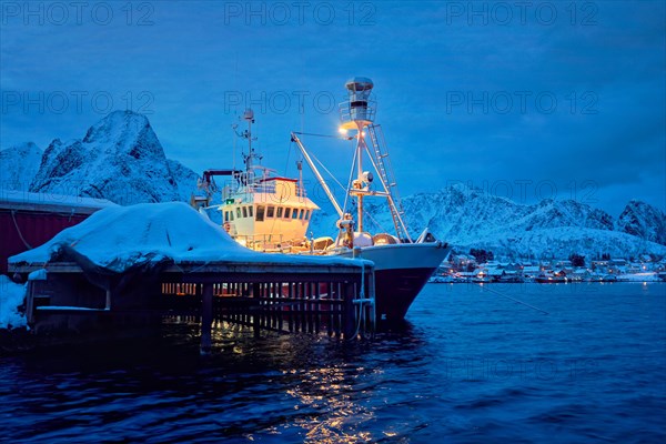 Fishing boat in Reine village illuminated at night in winter. Lofoten islands