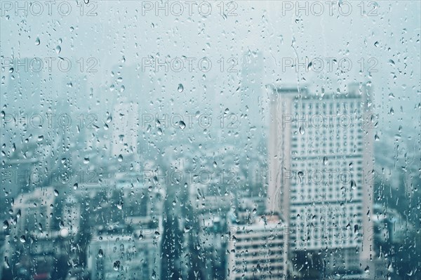 Rain water drops droplets on window glass texture with skyscrapers in background