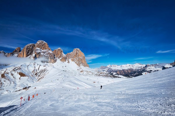 View of a ski resort piste with people skiing in Dolomites in Italy