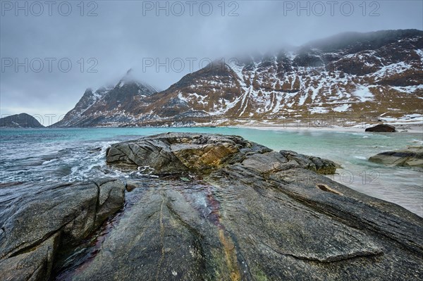 Rocky coast of fjord of Norwegian sea in winter with snow. Haukland beach