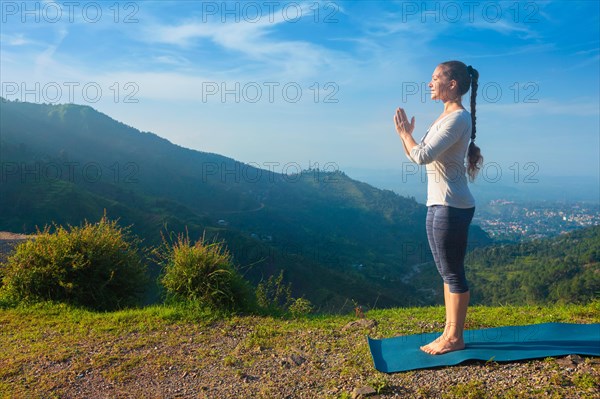 Woman doing Ashtanga Vinyasa Yoga asana Tadasana Samasthiti yoga posture in mountains in the morning