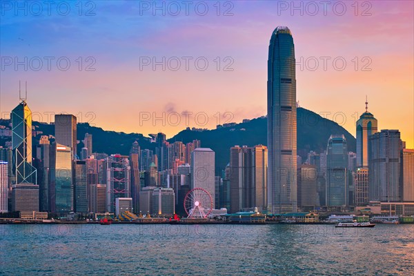 Hong Kong skyline cityscape downtown skyscrapers over Victoria Harbour in the evening with junk tourist ferry boat on sunset with dramatic sky. Hong Kong