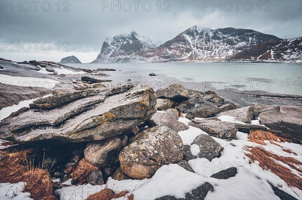 Rocky coast of fjord of Norwegian sea in winter with snow. Haukland beach