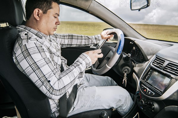Man sitting in his car texting with his cell phone