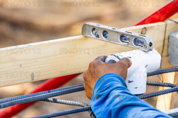 Plumber using level while installing PVC pipe at construction site