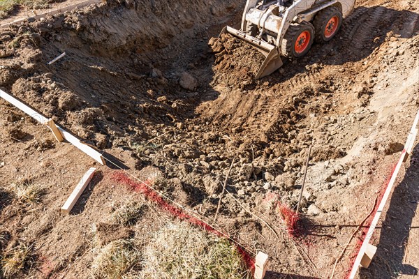 Small bulldozer digging in yard for pool installation