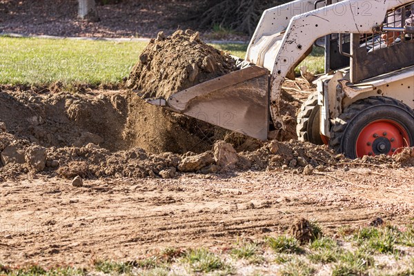 Small bulldozer digging in yard for pool installation