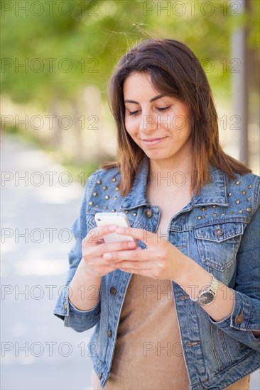 Beautiful young ethnic woman using her smartphone outside