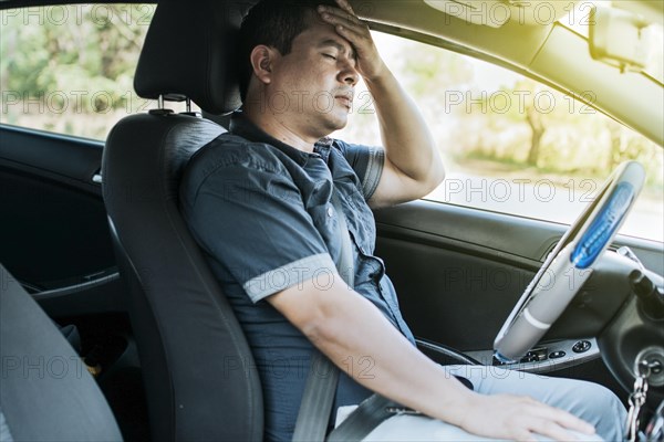 A person in his car with a headache