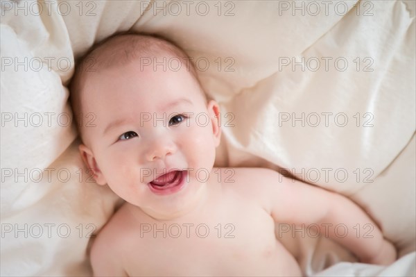 Young mixed-race chinese and caucasian baby boy having fun on his blanket