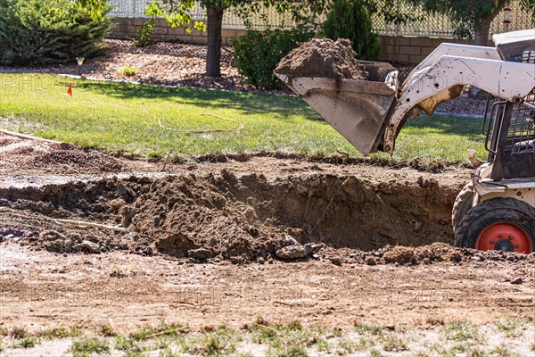 Small bulldozer digging in yard for pool installation