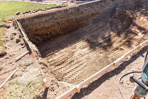 Freshly dug hole in yard preparing for swimming pool installation