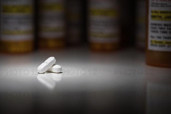 Hydrocodone pills and prescription bottles under spot light