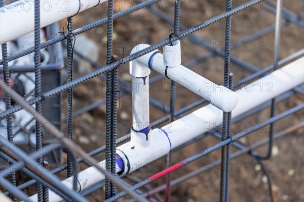 Newly installed PVC plumbing pipes and steel rebar configuration at construction site