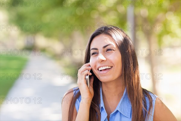 Beautiful young ethnic woman talking on her smartphone outside