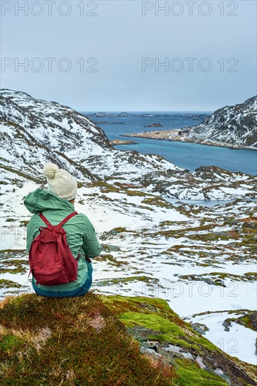 Woman tourist traveler enjoying a view of fjord in winter. Lofoten islands